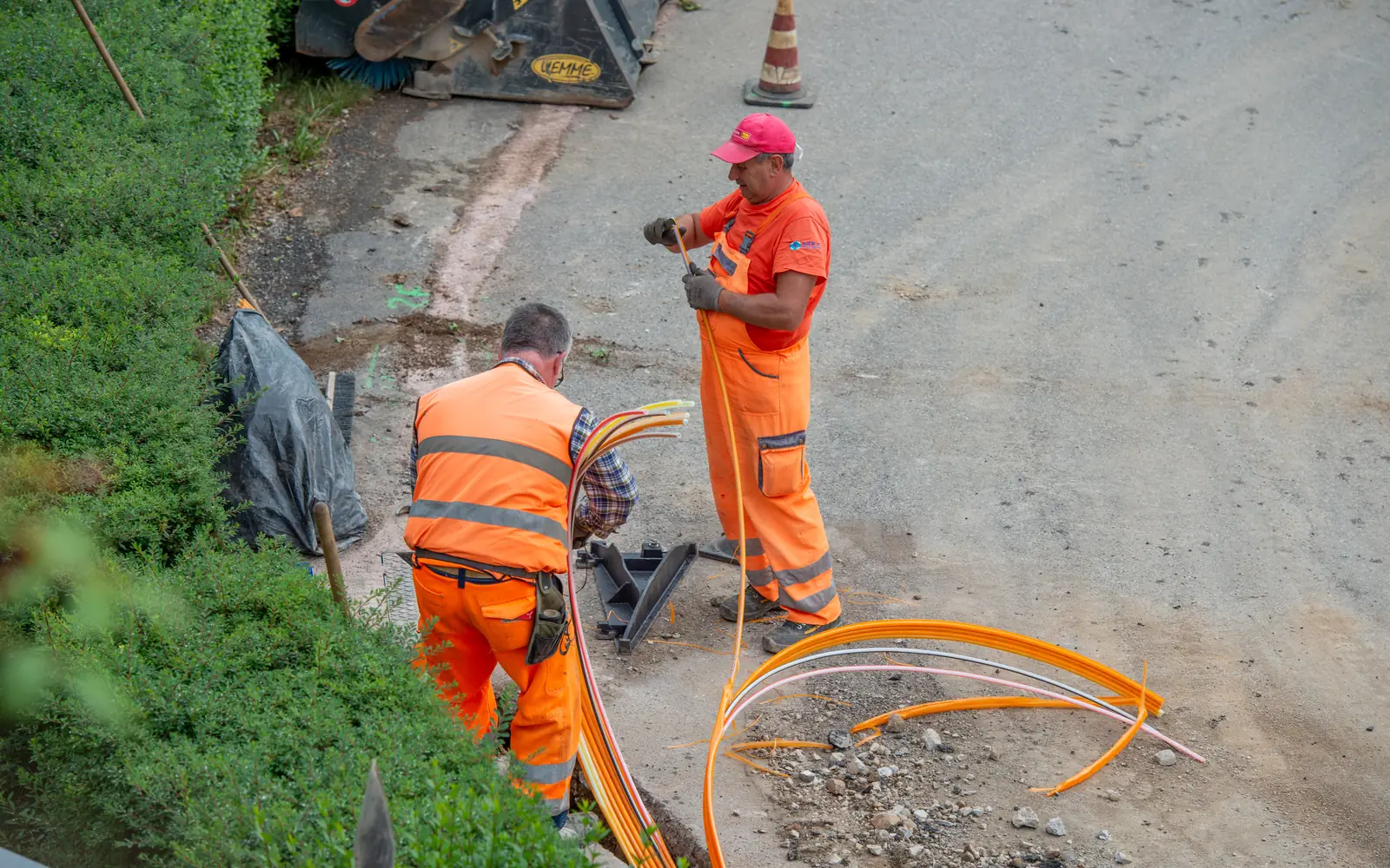 Kabeltiefbau für den Glasfaserausbau: Arbeiter verlegen Leerrohre im Graben
